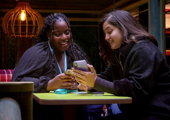 Two students smiling and looking at a phone